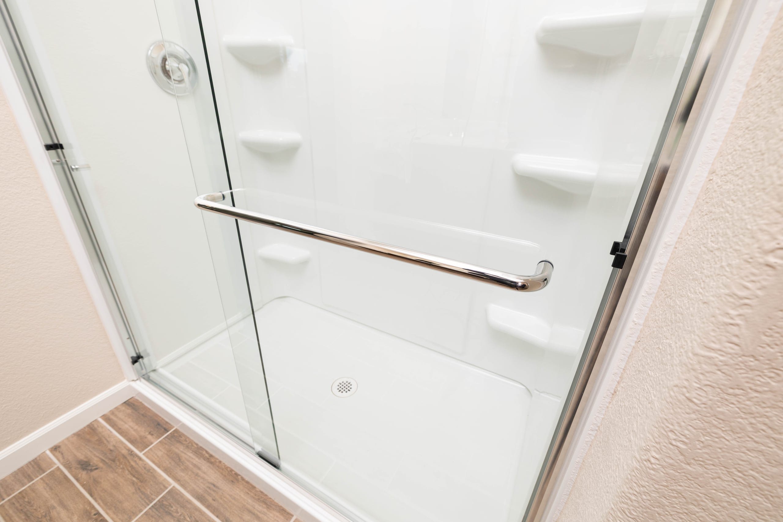 Long chrome bar pull handle on a frameless shower glass door