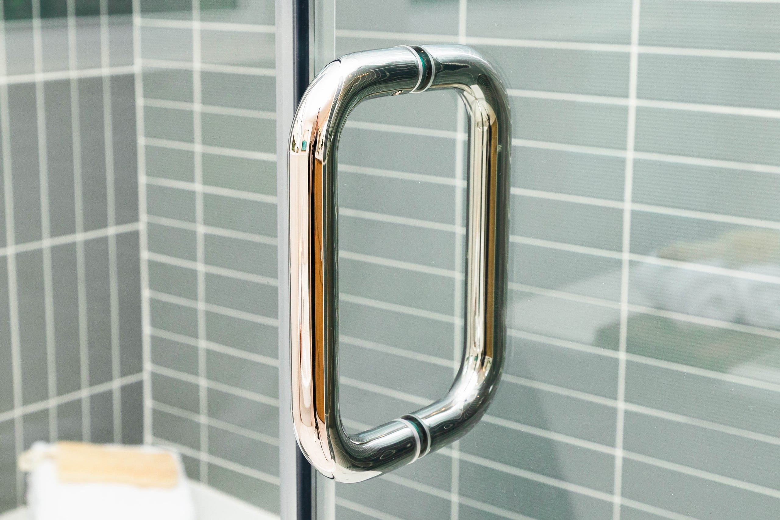 Chrome pull handle mounted on a frameless shower glass door