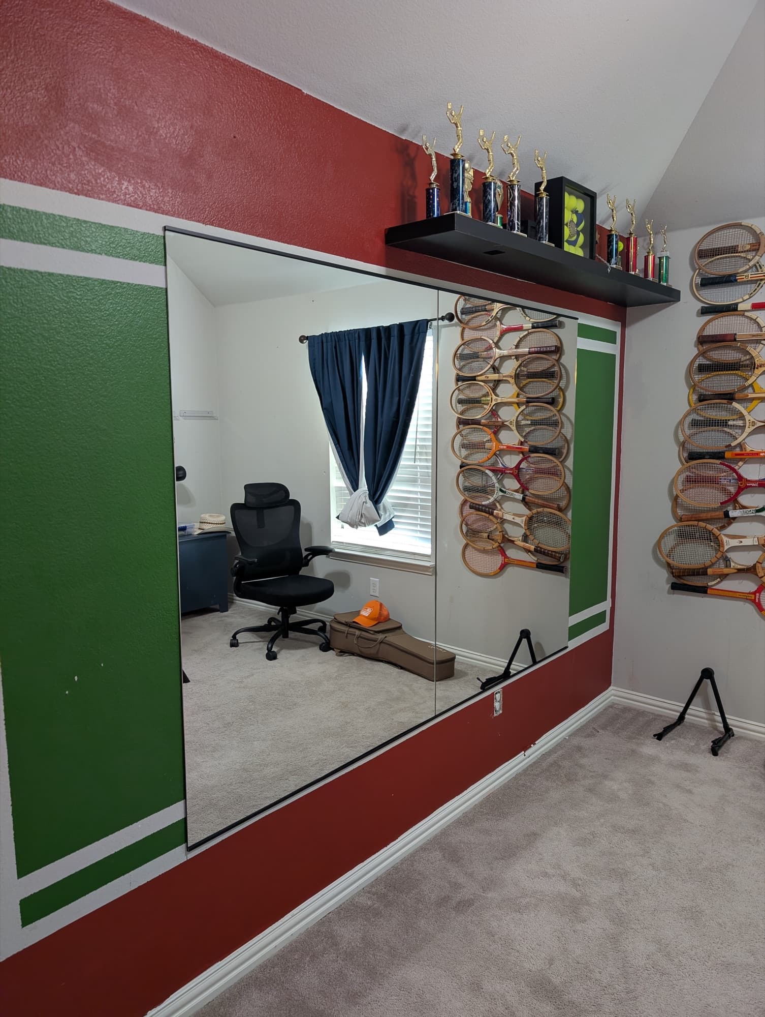 Two large wall mirrors held top and bottom by a matte black J-bar on a painted feature wall