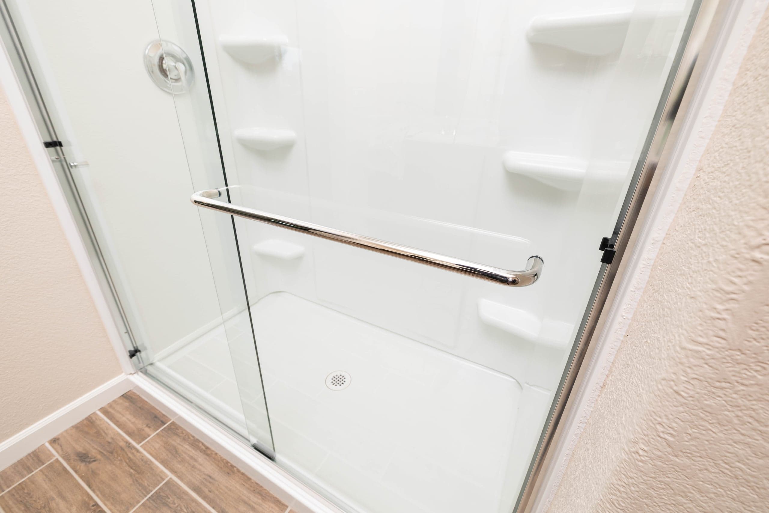 Long chrome bar pull handle on a frameless shower glass door — the full-length pull style used on sliding and bypass shower panels