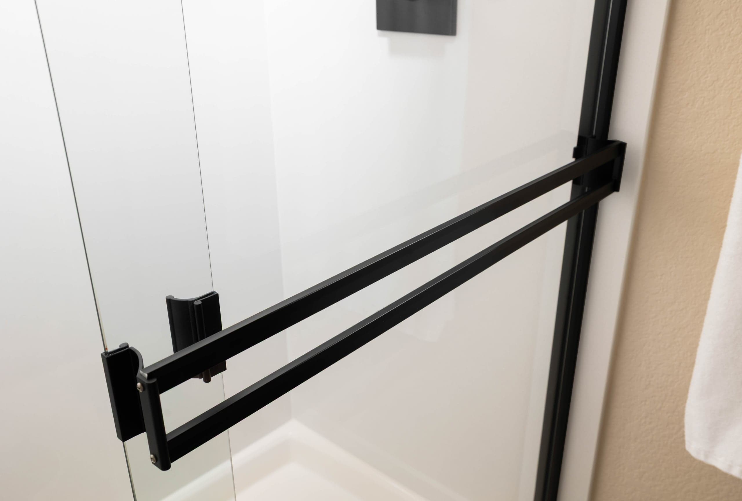 Matte black bar pull handle mounted on a large glass door panel — the full-length pull style used on interior glass barn doors