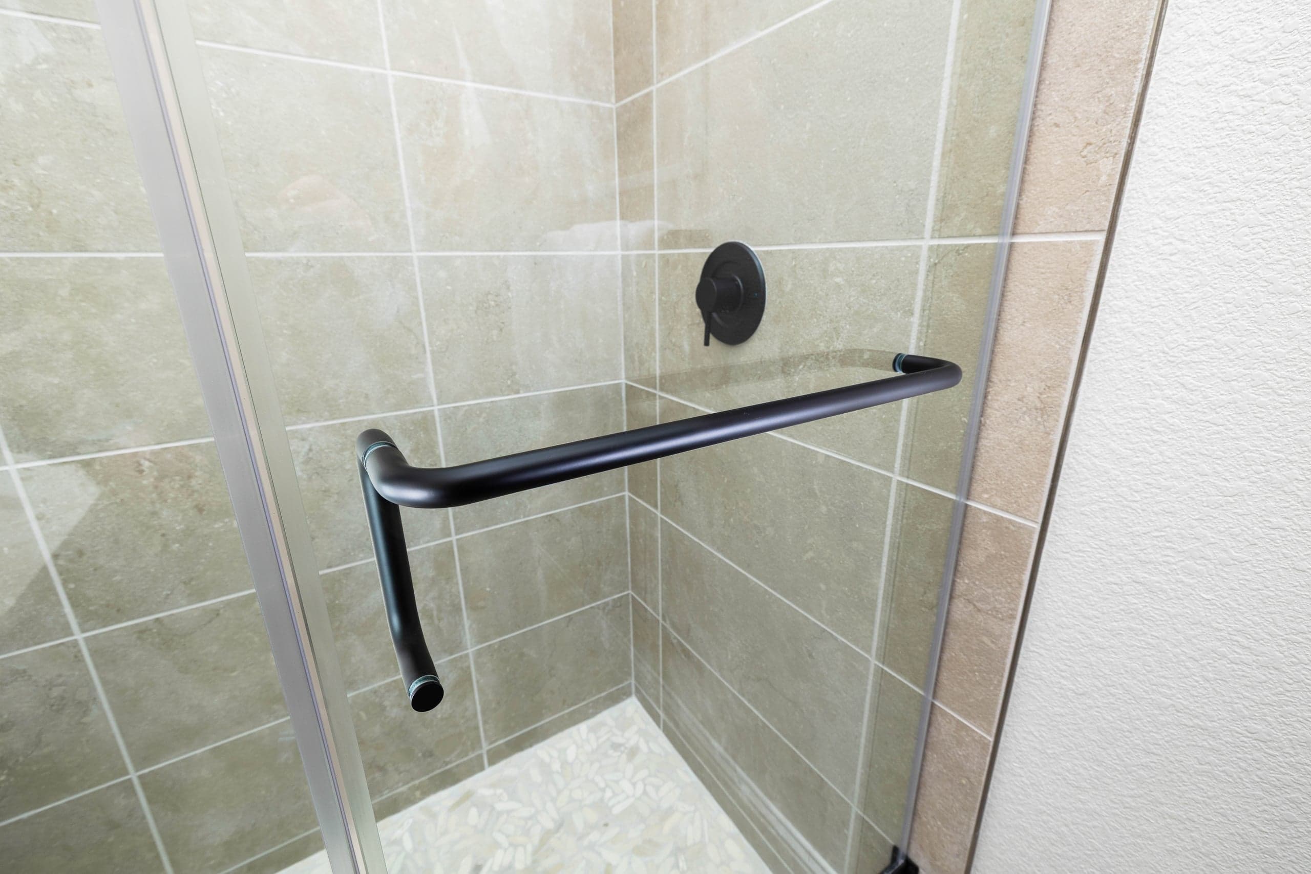 Hinged frameless shower door with matte black hardware in a Coppell Riverview-area primary bath