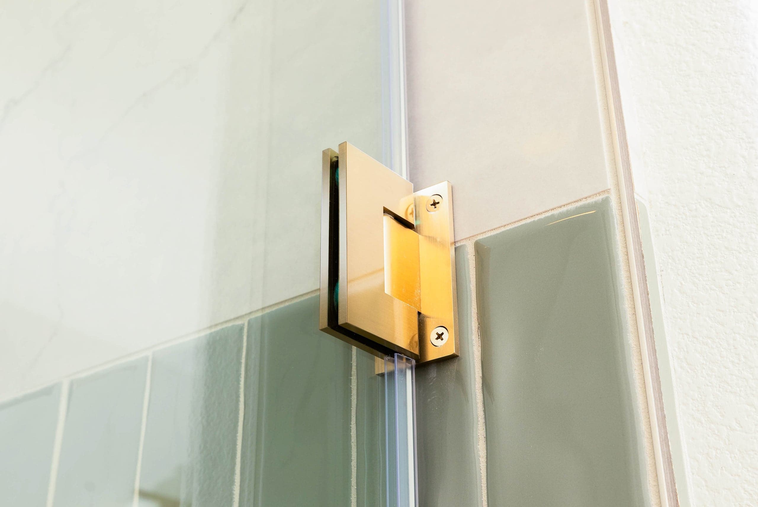 Frameless shower enclosure with brushed nickel hardware in a Plano Willow Bend primary bath showing precision mitered corner